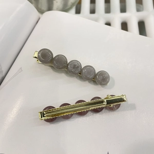 Set of two gold metal hair clips featuring gray marble resin beads and duckbill clasp