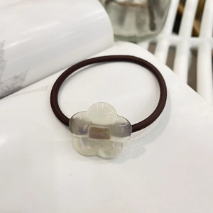 Detail of high-elastic hair tie featuring a pearlescent white flower with France Handmade text