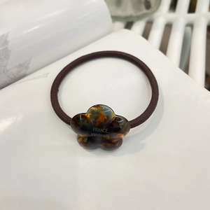 Close-up of tortoise shell resin flower elastic hair tie with gold France Handmade logo