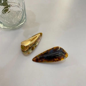 Detailed view of handmade marble and tortoiseshell hair clips on a clean white backdrop
