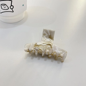 Elegant cream marble acetate hair claw clip with Barrette La France engraving on white desk