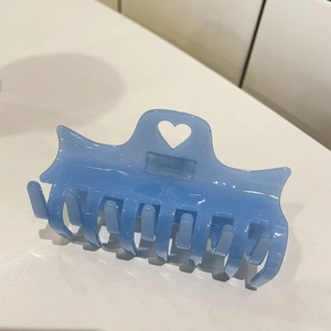 Détail de la pince à cheveux bleu clair en acétate avec paillettes et découpe en cœur