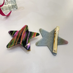 Detail von neon-gestreiften und glitzernden Stern-Haarklammern mit goldenem Entenschnabel