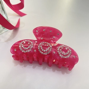 Dettaglio della pinza per capelli in acetato rosa marmorizzato con strass e molla