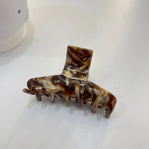 Detail view of acetate claw clip with tortoise shell pattern and gold Barrette lettering