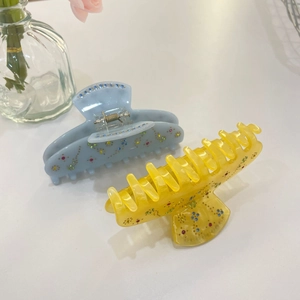 Detail showing colorful rhinestones on acetate hair claws in blue and yellow colors