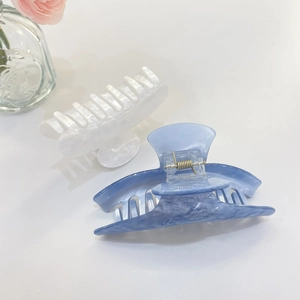 Dettaglio di due mollettoni per capelli effetto marmo blu e bianco con molla dorata