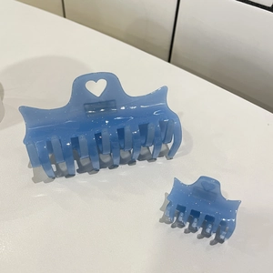 Détail de 2 pinces à cheveux bleues translucides à paillettes en acétate avec décors de cœur