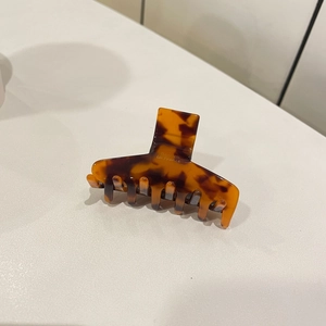 Detailed macro view of acetate hair claw with amber tortoiseshell texture and square handle