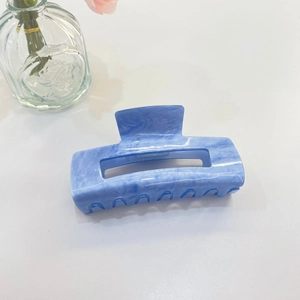 Dettaglio della molletta per capelli in acrilico blu marmo con design rettangolare