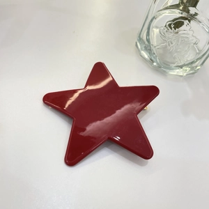 Detailaufnahme einer glänzenden roten Haarspange in Sternform mit polierter Harzoberfläche