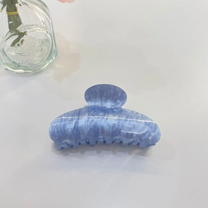 Dettaglio molletta per capelli azzurra con trama marmorizzata in acetato e denti a squalo