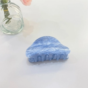 Dettaglio della molletta per capelli in acrilico blu marmorizzato con denti multipli