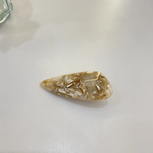 Detailed macro shot of amber brown and cream acetate hair clip with marble texture