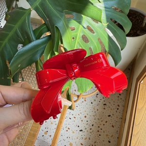 Detailed macro view of glossy red bow hair claw with elegant golden Handmade lettering