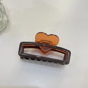 Brown acetate hair claw clip with amber heart detail and sturdy spring on white background
