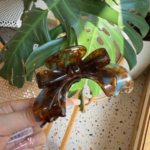 Detail of handmade tortoiseshell acetate hair claw clip with blue and brown bow design