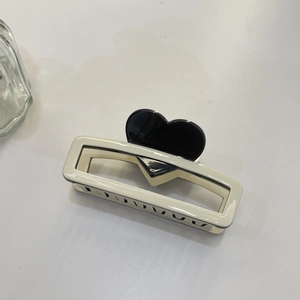 Detail of cream white rectangular hair claw clip with a glossy black heart accent