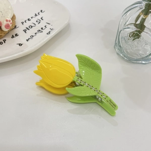 Detail of yellow tulip hair claw clip with rhinestones on a green leaf handle