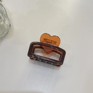 Detail of acetate square hair claw clip featuring amber heart handle and dark brown frame