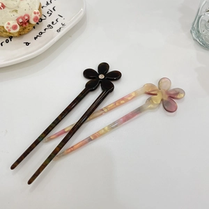 Detailed view of acetate flower hair sticks with sparkling rhinestones in a lifestyle setting