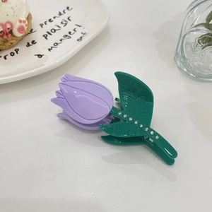 Detailed close-up of a purple tulip hair claw clip with rhinestones on a white table
