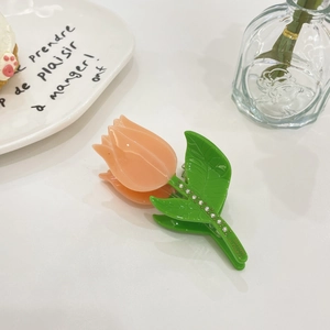 Detailed close-up of a tulip-shaped hair claw with rhinestones and orange petals