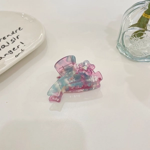 Gradient acetate hair claw clip with rhinestone flower on a minimalist white display