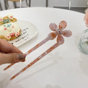 Detail of a pink floral acetate hair pin with crystal center in a stylish cafe setting