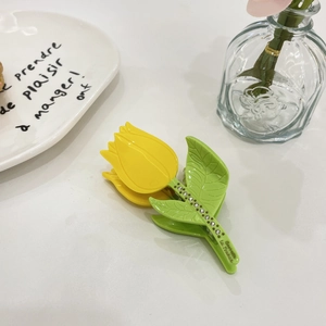 Detail of yellow tulip hair claw clip with green leaf and sparkling rhinestones