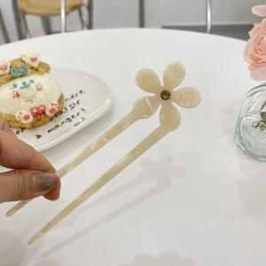 Detail of cream acetate flower hair pin with green gemstone inlay and double-tooth design