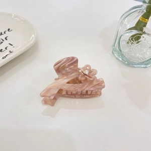 Detail of pink marble acetate hair claw clip with floral rhinestone accent on desk