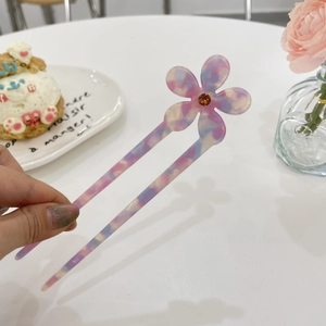 Detail of floral acetate hair fork with marble texture and sparkling rhinestone inlay