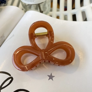 Detail view of a caramel resin bow hair claw clip with strong golden metal spring