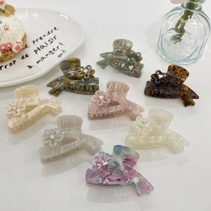 Detail of luxury acetate hair claws with flower patterns and crystal rhinestones