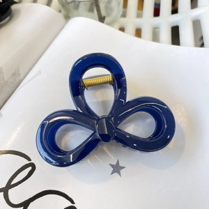 Detail of dark blue hair claw clip with golden spring on elegant decorative background