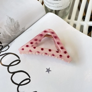 Pince à cheveux triangulaire rose à pois rouges sur un fond de magazine de mode