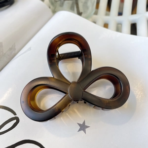 Close-up of tortoise shell bow hair claw clip with metal spring on a book page