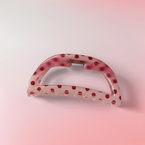 Vue détaillée d'une pince à cheveux rose à pois avec finition lisse et design courbé