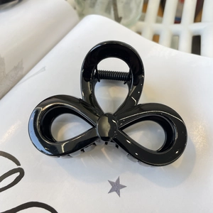 Close-up of glossy black triple-loop bow hair claw clip with strong metal spring