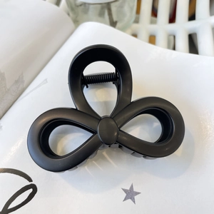 Detail of matte black butterfly hair claw clip with metal spring on decorative paper