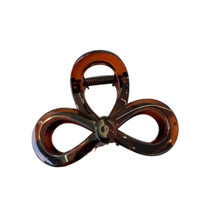Elegant amber tortoiseshell bow hair claw clip with minimalist cutout design on white background