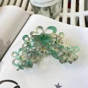 Detail einer floralen Haarklammer mit grünem Acetat-Marmor-Muster und gelben Mitten