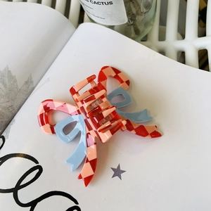 Close-up of pink and red checkered bow hair claw clip with blue ribbon details