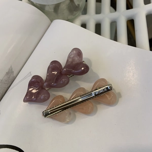 Détail de barrettes à cheveux cœur en acrylique marbré violet et pêche avec base en métal