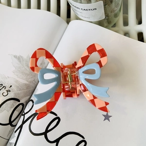 Detail of red checkered and blue bow hair claw clip on a magazine aesthetic setting