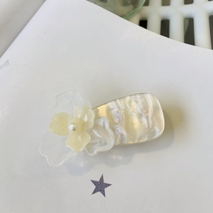 Détail d'une pince à cheveux fleurie avec pétales 3D et perle blanche centrale