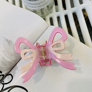 Detail of pink double-layered bow hair claw clip with golden metal spring