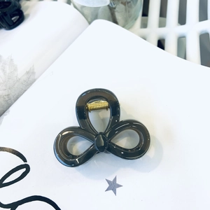Close-up of translucent smoke gray resin hair claw clip with golden metal spring