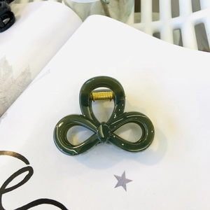 Detailed view of dark green bow hair claw clip with a glossy finish and golden spring
